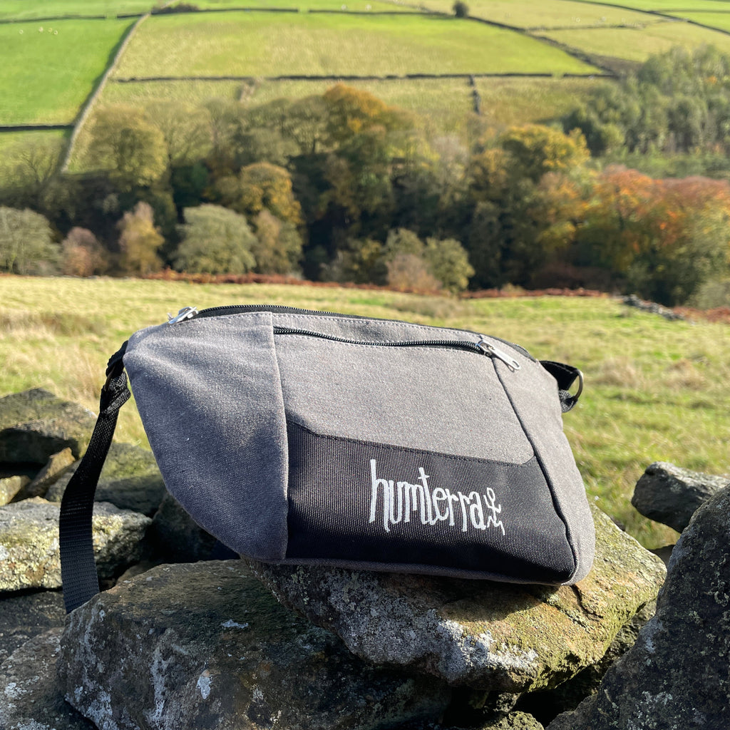Gray bag with 'humera' branding on a stone wall with a scenic background