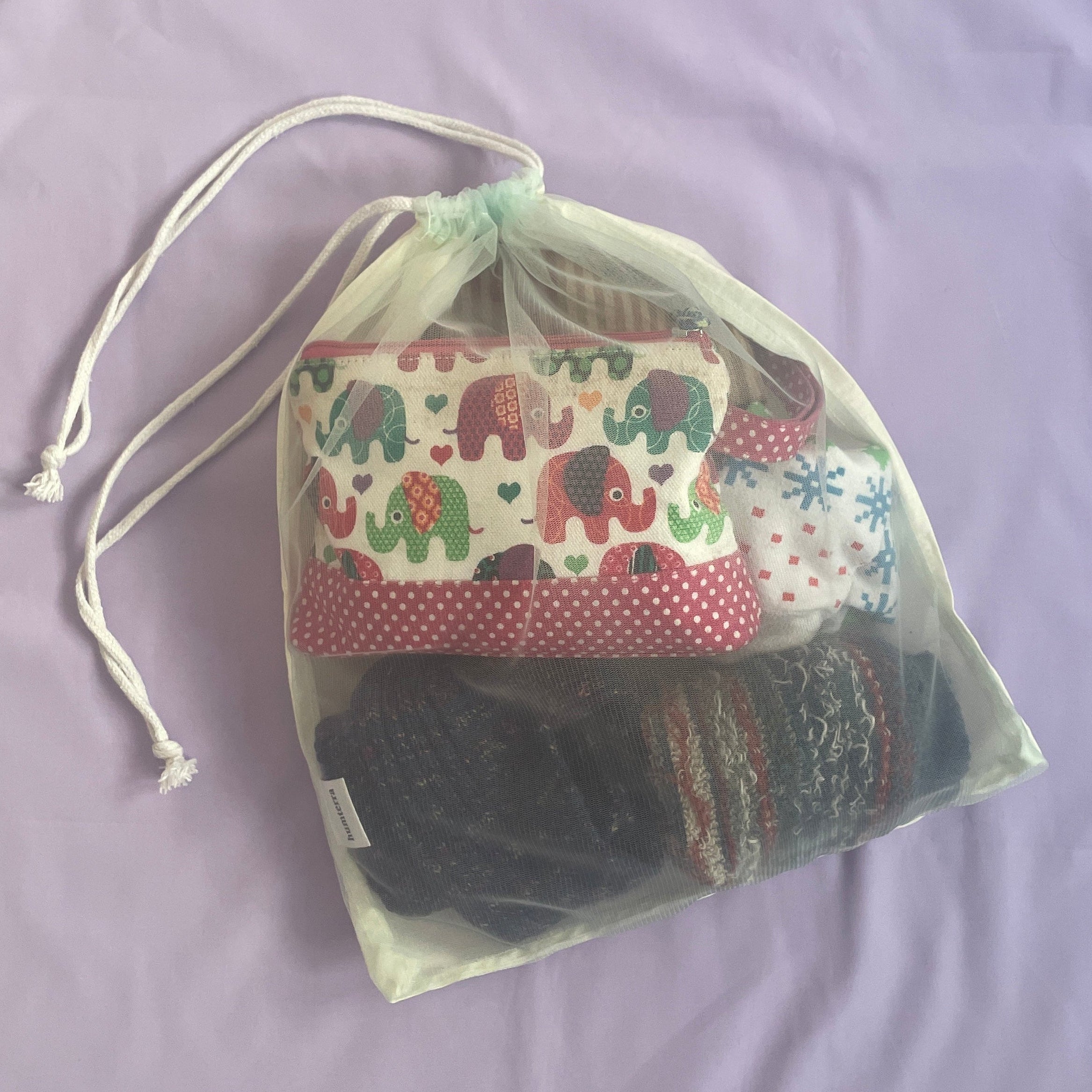 Drawstring bag with various items on a purple background