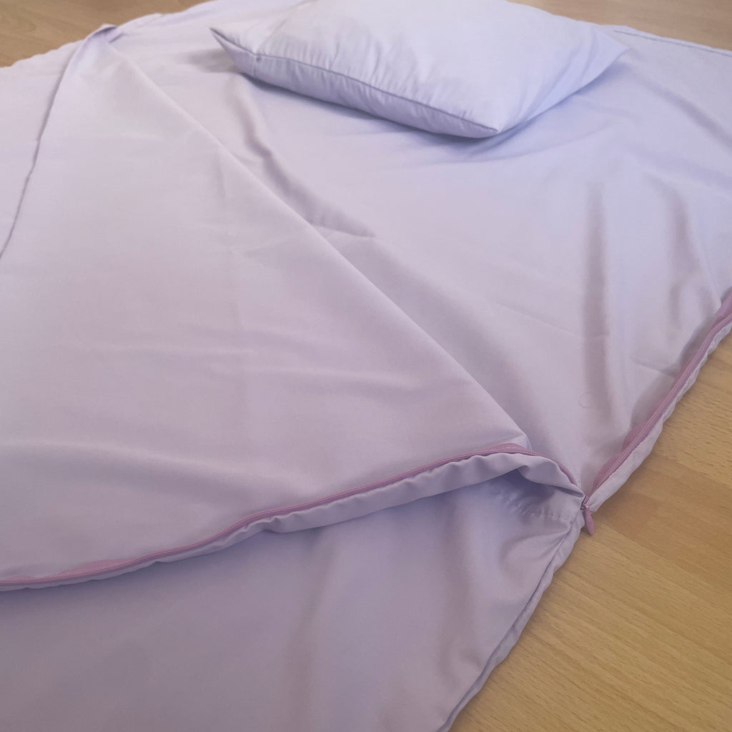 Purple sleeping liner with a matching pillow on a wooden surface