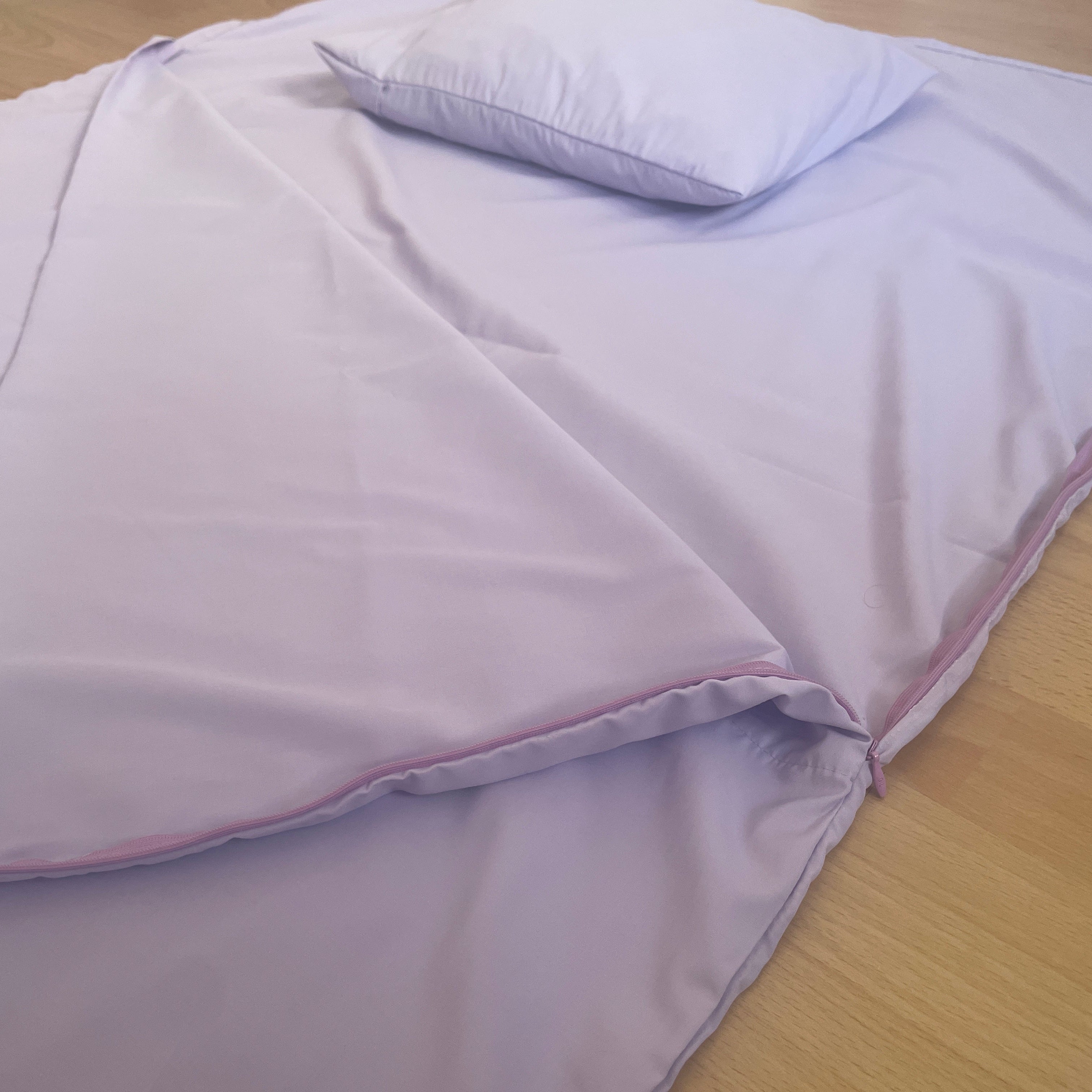 Purple sleeping liner with a matching pillow on a wooden surface