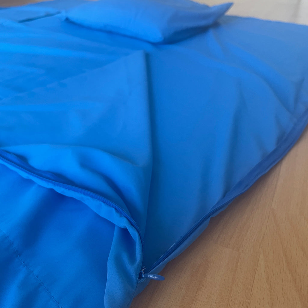 Blue sleeping liner with a pillow on a wooden floor