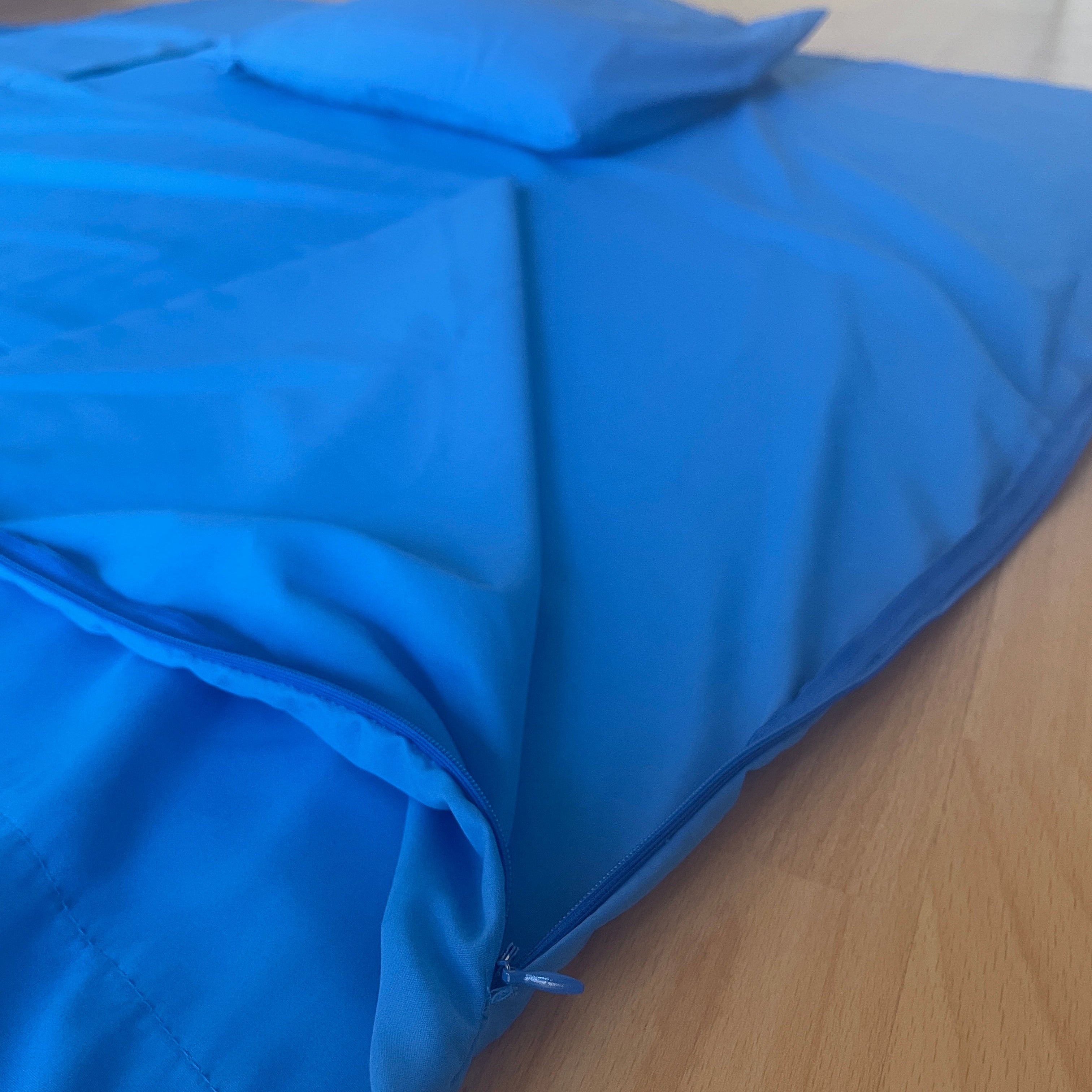 Blue sleeping liner with a pillow on a wooden floor